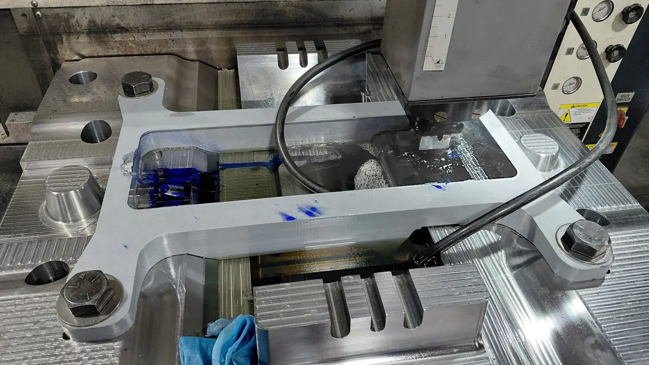 Custom gray 3D-printed EDM tank installed around a workpiece during machining